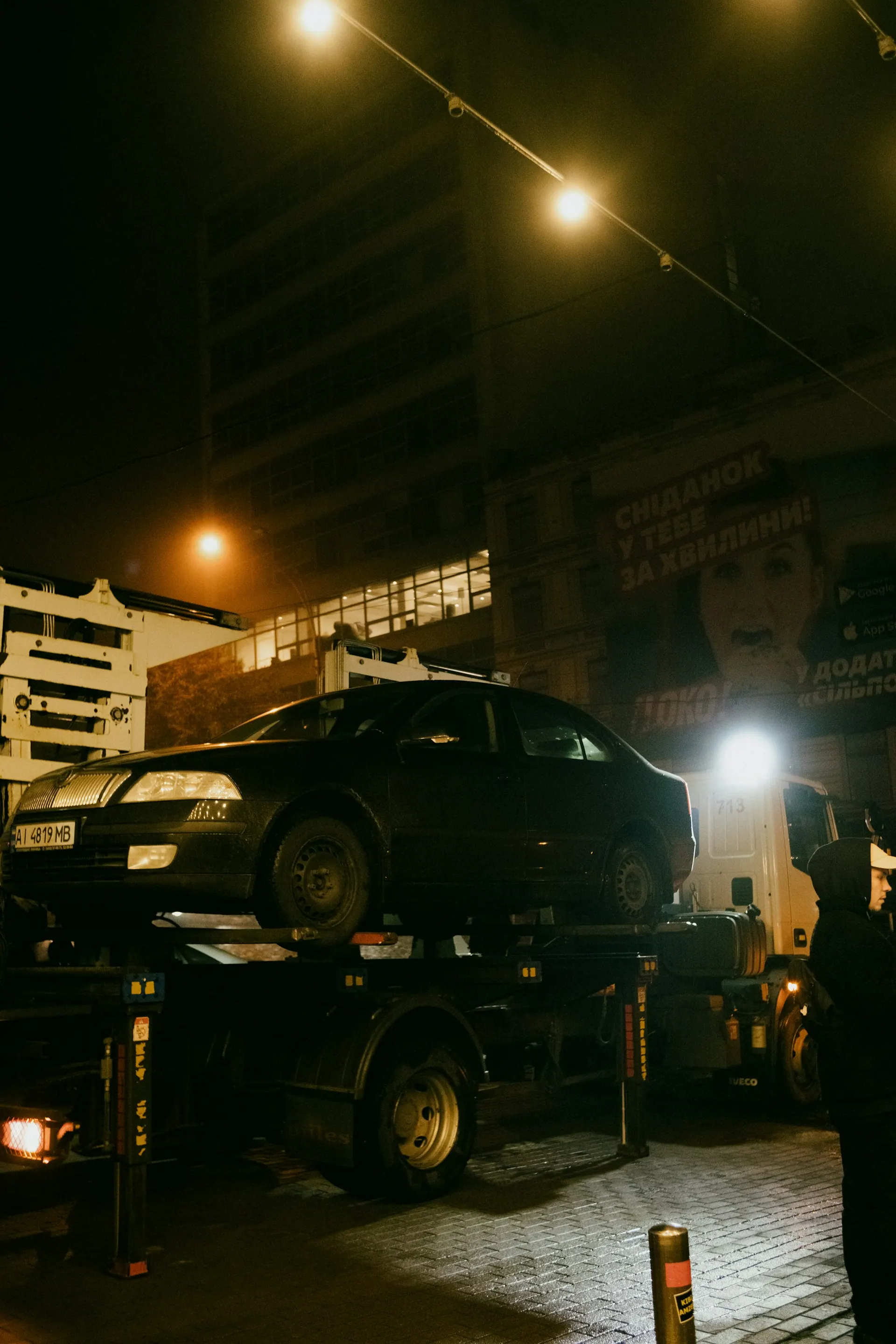 Tow truck assisting a vehicle on a dark roadside